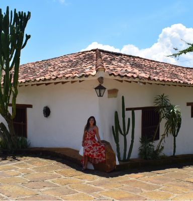 Casa antigua rodeada de cactus y una mujer con vestido rojo